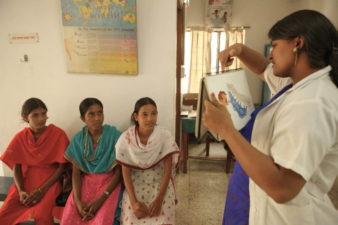 Un agent de santé explique les symptômes de la tuberculose à des jeunes femmes.
